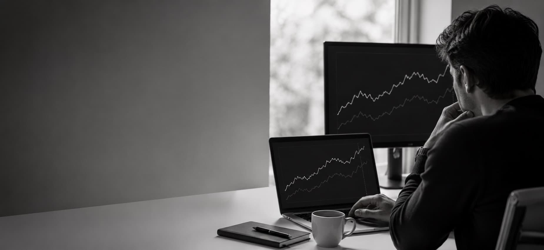 Analyst at a desk watching two price curves on a monitor during a live match